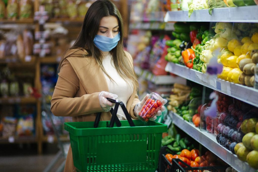 Grocery shopper with mask and gloves carrying basket